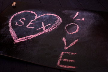 Heart and sex drawn on a black background. The concept of love and the relationship between the sexes.