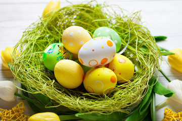 Fototapeta na wymiar Happy Easter. Congratulatory easter background. Easter eggs and flowers. Background with copy space. Selective focus. Top view.