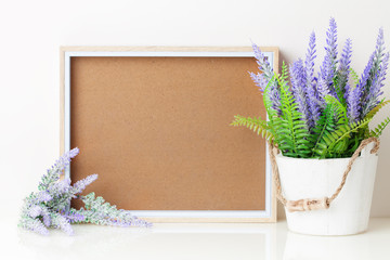 Frame and flowers on the table. White colors. Greeting card. Background with copy space. Mock up.