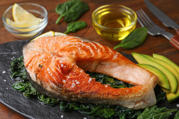 Tasty salmon with spinach served on table, closeup