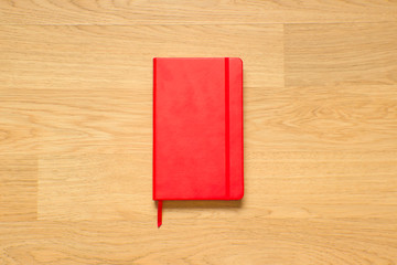 Red sketchbook close-up on the wooden table. Stylish notebook for painting, drawing and writing.
