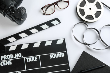 Composition with camera and clapboard on white background, top view. Video production industry - obrazy, fototapety, plakaty