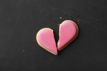 Broken heart shaped cookie on black table, top view with space for text. Relationship problems...