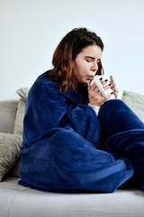 The young girl drinks tea on mit royal blue warm blanket