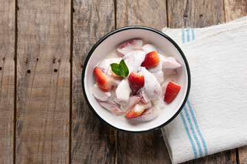 Strawberries and cream dessert on wooden background