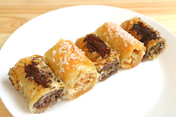 Plate of Roll Shaped Baklava Pastries in Different Flavors Served on Wooden Table	