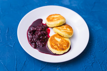 Cottage cheese pancakes with cherry jam, close up, top view.