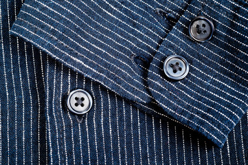 The texture of a denim shirt in dark blue with a small strip on the buttons. Background for fabric and clothes. Fashion, style and practicality.