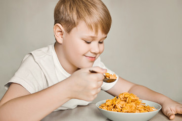 The boy at the table enjoys eating breakfast cereal with milk