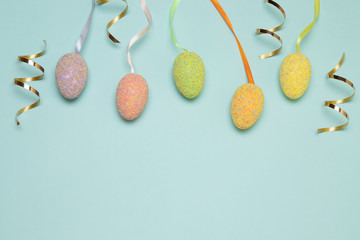 multicolored easter eggs, dragee candies and gold candy on a blue background, top view