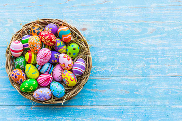 Easter holiday concept,Colorful Easter eggs in basket on blue pastel color rustic wood background with space.