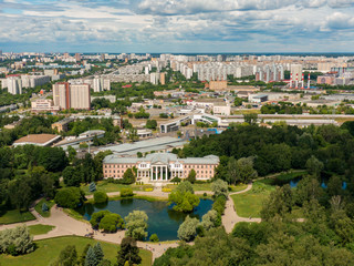 Fototapeta na wymiar The main Botanical Garden in Moscow near a beautiful pond, in the background is a city transport hub, public transport and metro stops, urban development. Aerial photography