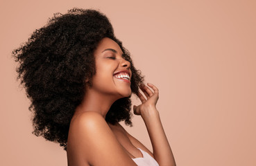 Happy young African American woman on pink background