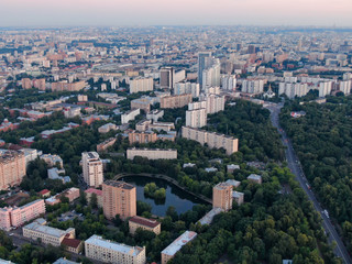 Fototapeta na wymiar Evening Moscow from above, in the frame of a house and a street, a lake in the yard of a house and a road with cars, city everyday life. Aerial photography