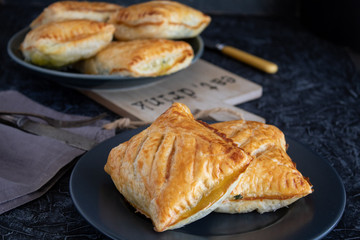 Fresh baked puff pastry buns with spinach on a grey background