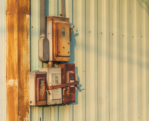 The electrical circuit box that is old and rusty was installed next to the wall of the factory.
