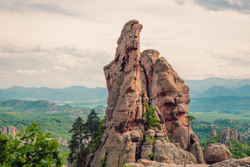 A beautiful rock formation against the backdrop of a green mountain valley, a high reddish rock...