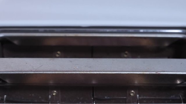 Roasted bread jump out from a white toaster. close-up view of pastries in process a toasting device
