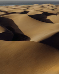 Fototapeta na wymiar Boy standing in the middle of desert, sand dunes in Canary Islands aerial view.