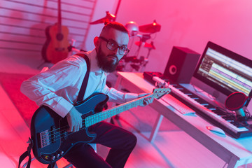 Create music and a recording studio concept - Bearded funny man guitarist recording electric guitar track in home studio