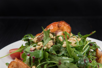 Green salad with shrimps: greens, arugula, tomato, pine nuts and sauce