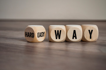 Cubes and dice with words hard way or easy way on wooden background