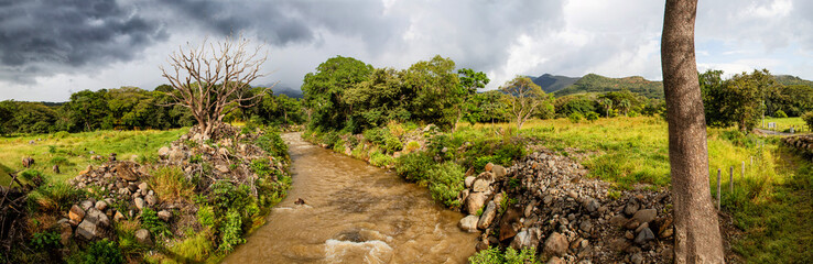 Fototapeta na wymiar Landscape with a river and volcanoes in the background in the interior of Costa Rica between La Fortuna and Bijagua made by different photos stitched together.