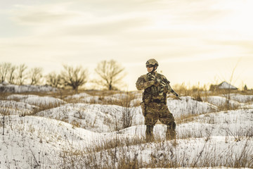 equipped army soldier Man in the winter khaki camouflage is patrolling or patrol field territory....