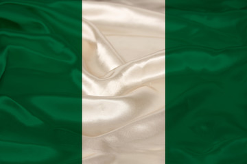 Obraz premium photo of the national flag of Nigeria on a luxurious texture of satin, silk with waves, folds and highlights, closeup, copy space, travel concept, economy