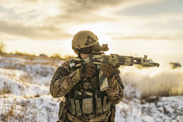 Fototapeta premium equipped army soldier Man in the winter khaki camouflage is patrolling or patrol field territory. commandos with full equipment helmet and gun watch battlefield. Modern army soldier