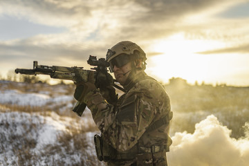 Fototapeta premium equipped army soldier Man in the winter khaki camouflage is patrolling or patrol field territory. commandos with full equipment helmet and gun watch battlefield. Modern army soldier