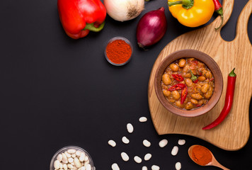 Macedonian bean dish Tavche graver on a wooden board next to the ingredients on a black background. copy space