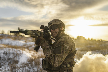 equipped army soldier Man in the winter khaki camouflage is patrolling or patrol field territory. commandos with full equipment helmet and gun watch battlefield. Modern army soldier