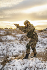 Naklejka premium equipped army soldier Man in the winter khaki camouflage is patrolling or patrol field territory. commandos with full equipment helmet and gun watch battlefield. Modern army soldier