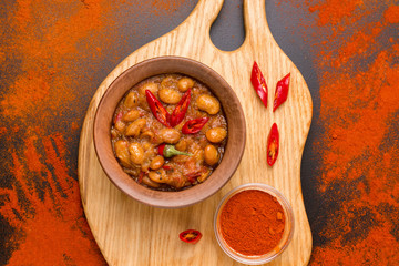 a dish of Macedonian cuisine Tavce graver in a clay bowl on a black background close-up next to sprinkled spices
