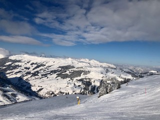 Empty snowy skiing slope in the mountains with blue cloudy sky