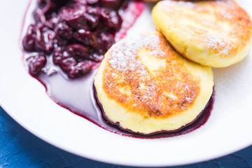 Cottage cheese pancakes with cherry jam, close up, top view.