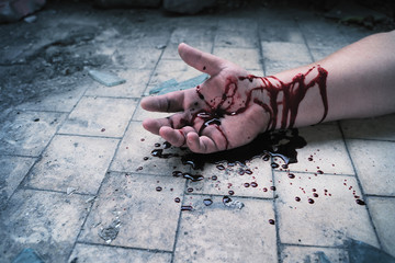 Crime scene with hand in blood on floor of killed man by murder, close up. © DedMityay