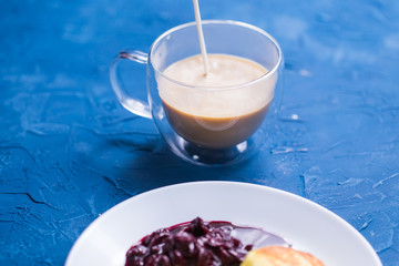 Cottage cheese pancakes with cherry jam, close up, top view. Pouring coffee into a cup.