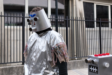 Two vintage silver robots walking in the street. Man in carnival costume at the Pust parade. San...