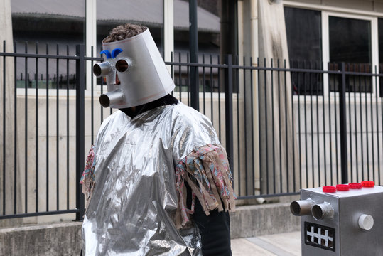 Two vintage silver robots walking in the street. Man in carnival costume at the Pust parade. San Pietro al Natisone, Udine province, Friuli Venezia Giulia region, Italy.