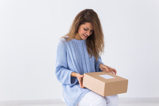 Online shopping, delivery and fashion concept - Woman sitting on sofa at home opening online clothing purchase