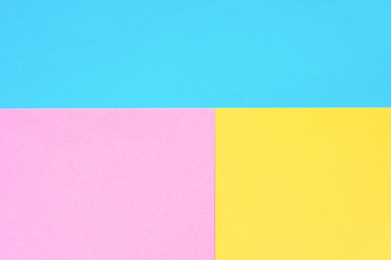 Blue, yellow and pink colored paper. Geometric empty paper background of three tones for copy space.