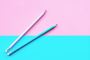 Two pink and blue wooden pencils on colored paper background. Education concept. Top view, flat lay, copy space.