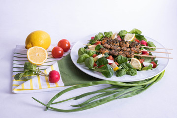lunch of shrimp on sticks and vegetables in a white plate on a table