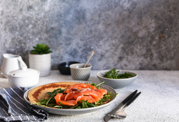 Crepe with arugula and salmon for breakfast on the kitchen table. Good morning.
