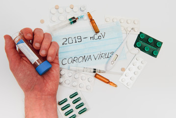 a test tube with a positive test for the CAVID-2019 coronavirus. medical devices on a white table. thermometer, phonendoscope, tablets, surgical masks