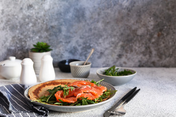 Crepe with arugula and salmon for breakfast on the kitchen table. Good morning.