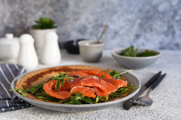 Crepe with arugula and salmon for breakfast on the kitchen table. Good morning.