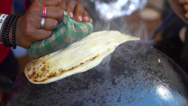 Man making an ulta tawa paratha bread on an upturned pot mughal cuisine from india and pakistan